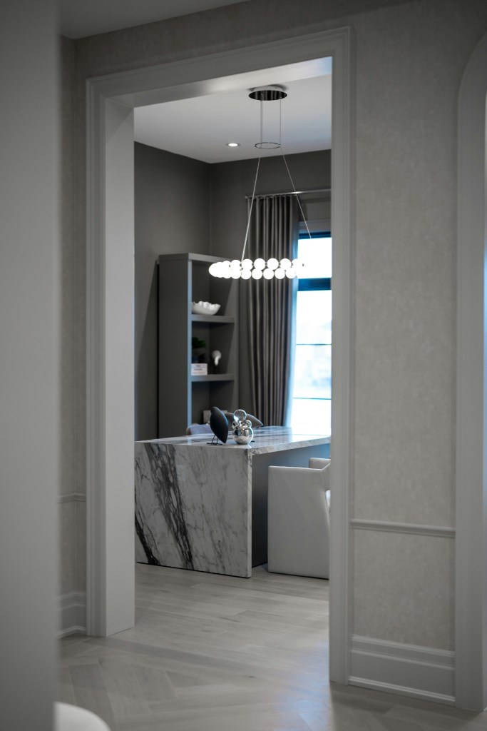 View through a doorway into a refined modern workspace, suggesting depth and discovery.